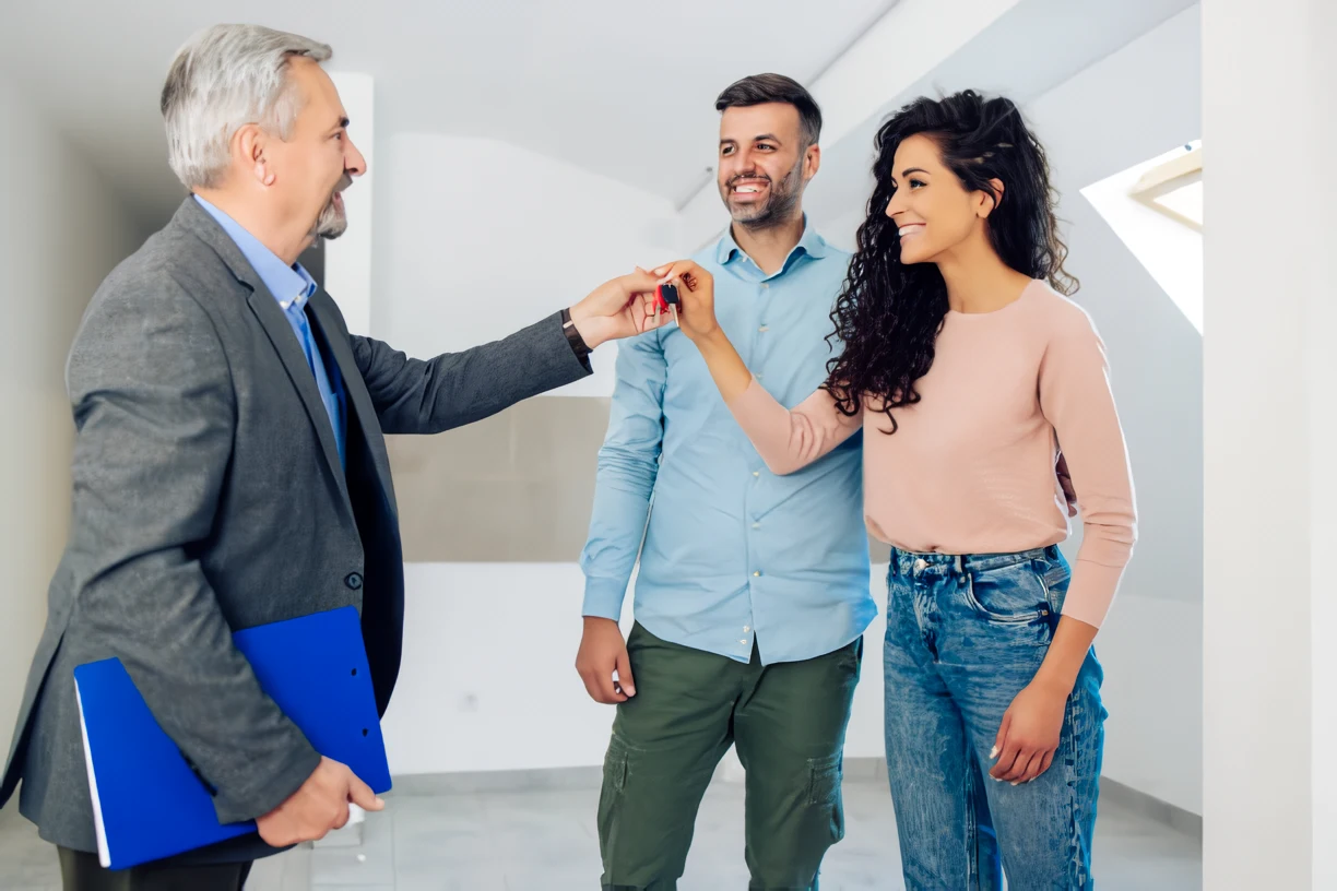 Persona entregando las llaves de la vivienda a una pareja