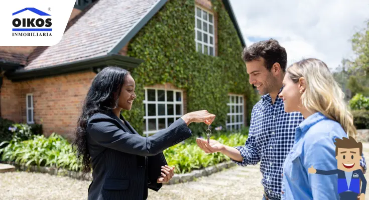 Clientes con agente inmobiliaria recibiendo las llaves de su vivienda