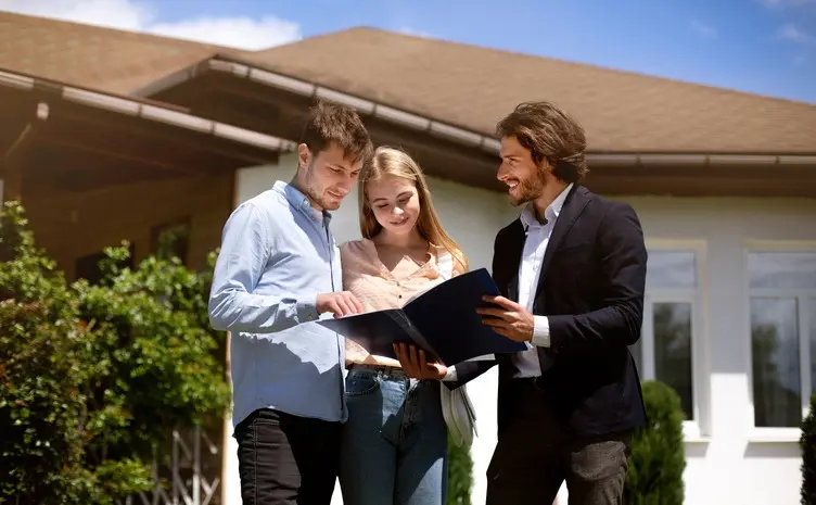 ¿Cómo un avalúo profesional mejora decisiones de compra o venta? Agente inmobiliario mostrando inmuebles a pareja joven