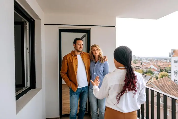 Pareja en un balcón con una asesora inmobiliaria