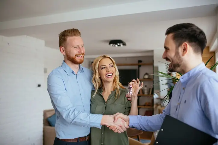 ¿Qué tipo de inmueble te conviene para 2026? pareja feliz recibiendo las llaves de su inmueble
