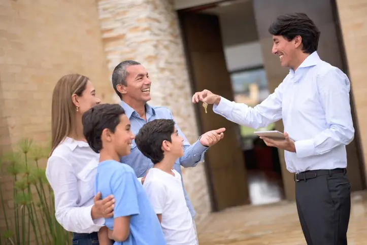 ¿Qué elegir: casa o apartamento para vivir o invertir? Agente inmobiliario entregando llaves de una casa a una familia