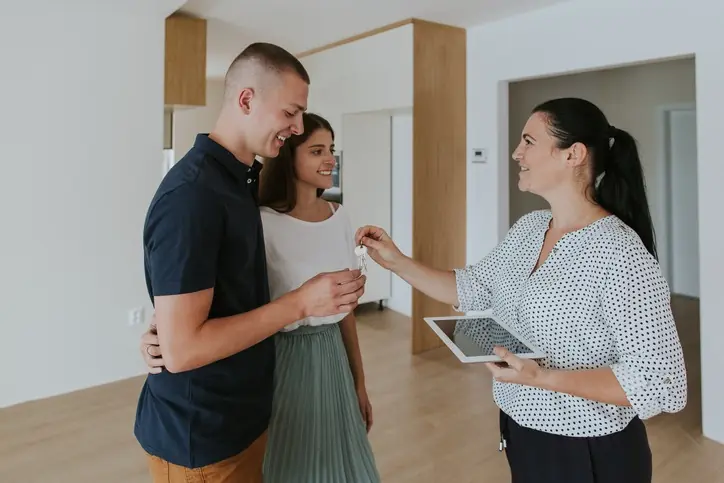 Ventajas de arrendar con el acompañamiento de una inmobiliaria profesional como OIKOS Inmobiliaria Agente inmobiliaria entregando llaves de un inmueble a una pareja