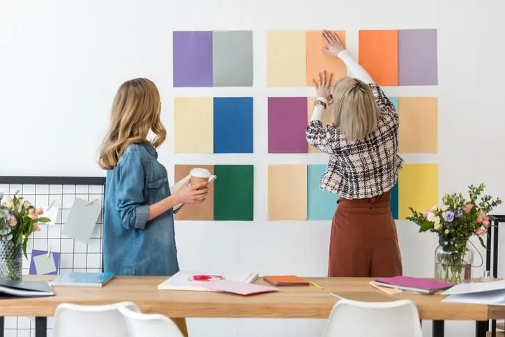 Mujeres eligiendo paleta de colores en pared