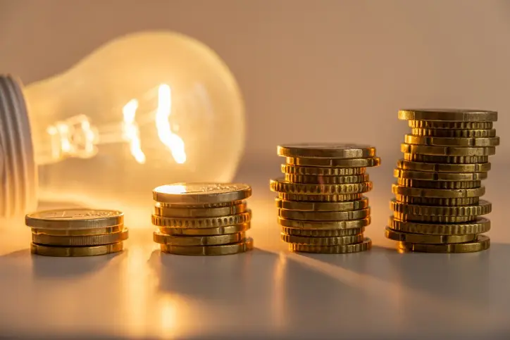 Costos mensuales de administración Monedas iluminadas por un bombillo