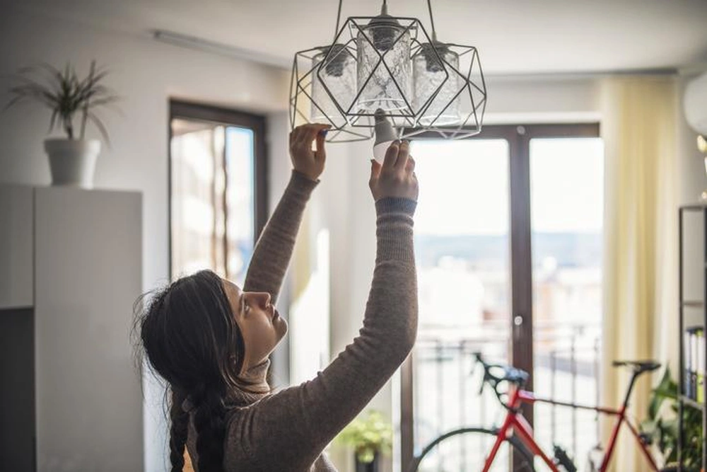 Mujer organizando lámpara Home staging: primera impresión que acelera decisiones