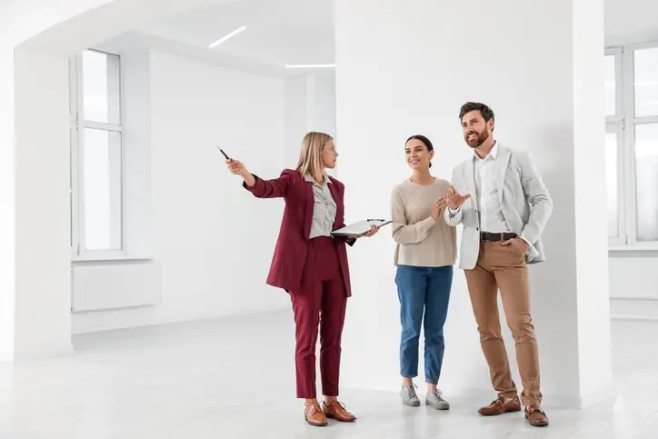 ¡Invierte con respaldo real: OIKOS Inmobiliaria está contigo! Agente inmobiliaria mostrando un inmueble a una pareja