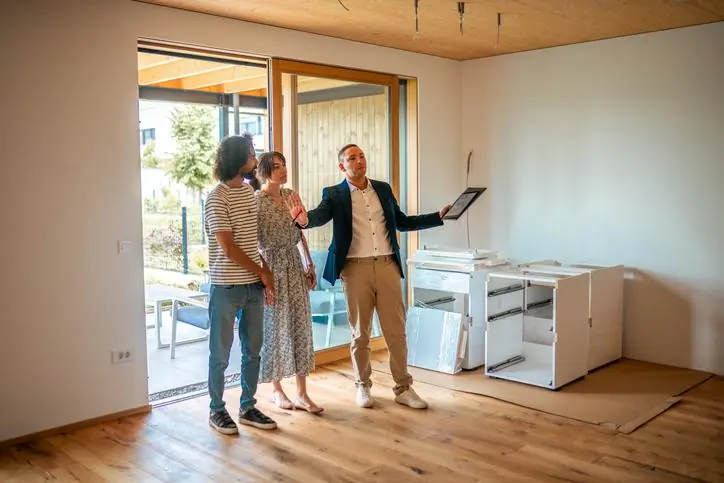 Beneficios de vender tu inmueble con el respaldo de una inmobiliaria Personas viendo un inmueble con un asesor inmobiliario