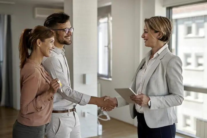 ¿Por qué confiar en OIKOS Inmobiliaria para vender tu propiedad? Asesora inmobiliaria dando la mano a pareja interesada en vivienda